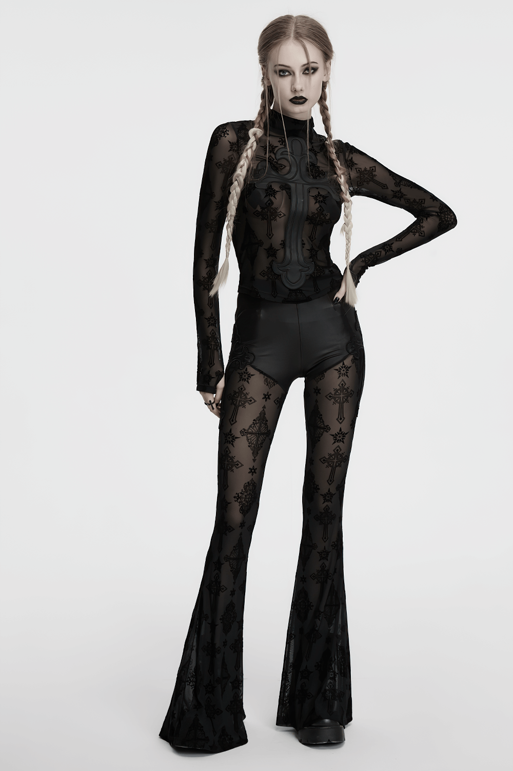 Chic goth model in black mesh and faux leather flared pants showcasing cross embroidery and layered design.