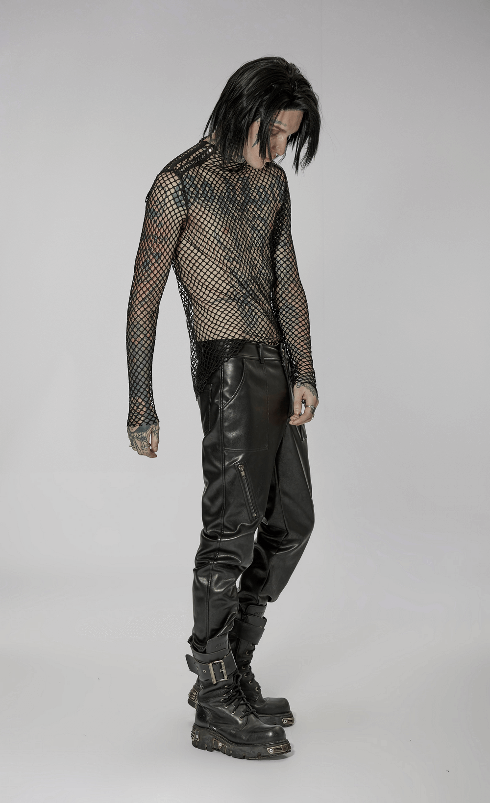 Stylish gothic punk model in sheer fishnet mesh top and black leather pants, showcasing edgy fashion vibes.