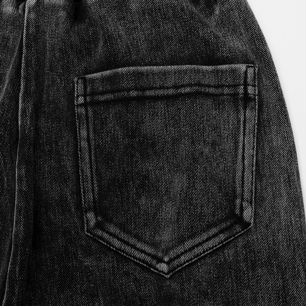 Close-up of washed black fabric with pocket detail on stylish Gothic flared pants for women.