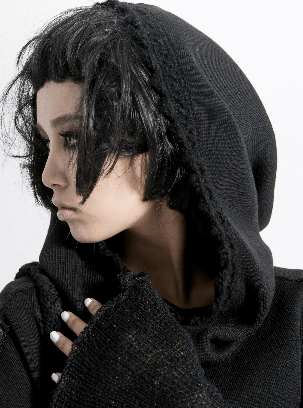 Close-up of a woman wearing a black hooded wrap cape, showcasing gothic style and a punk rave aesthetic.