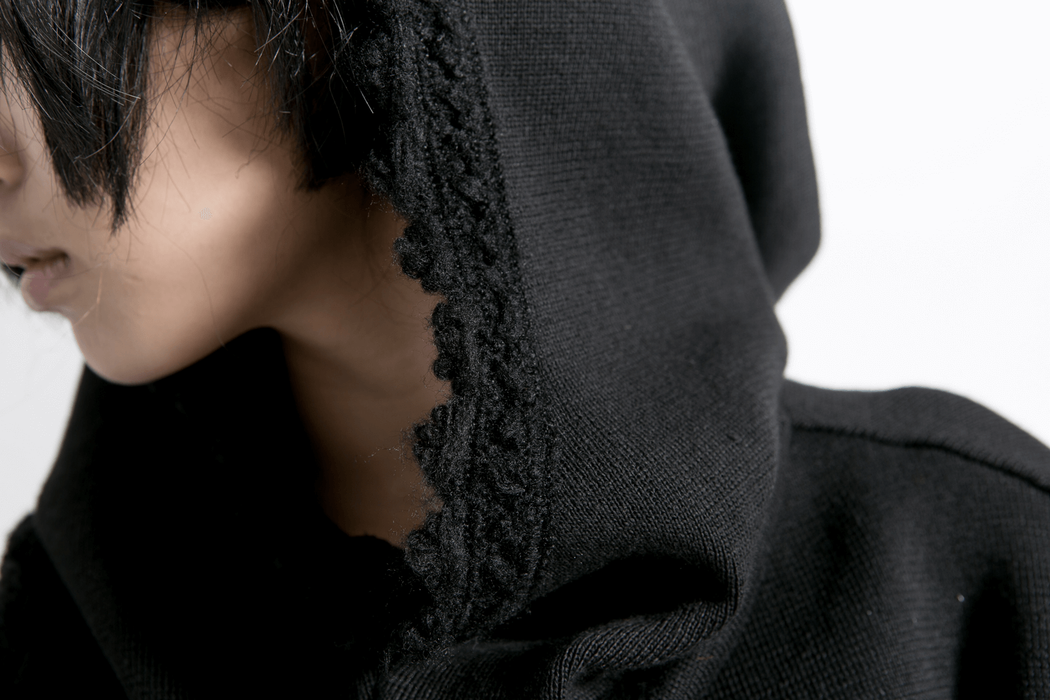 Close-up of a stylish black hood on a gothic knitted cape, showcasing intricate edge details and a mysterious vibe.