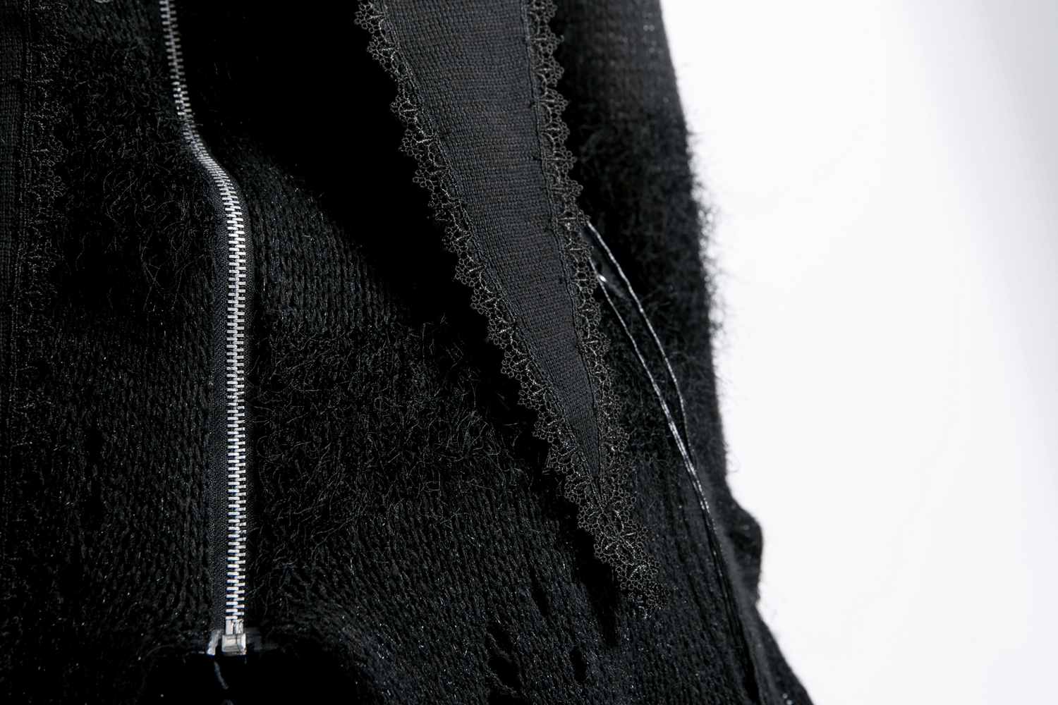 Close-up of a stylish black wool hooded wrap cape featuring a zipper detail and textured fabric.