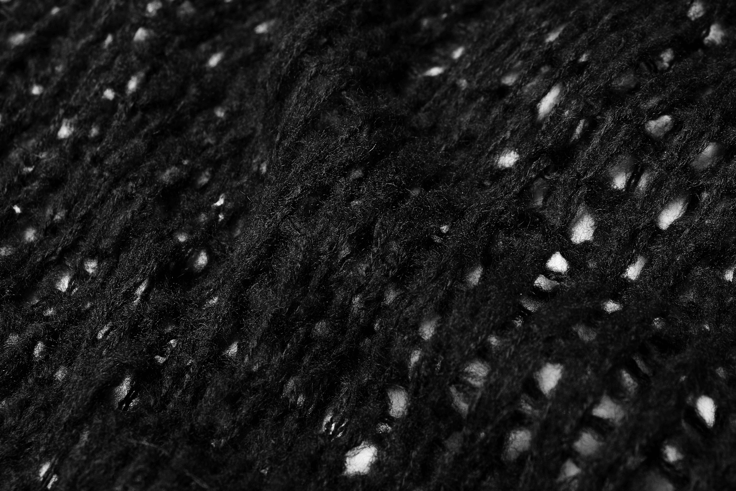 Close-up of a black knit mesh fabric showcasing intricate design and breathability for stylish pullovers.