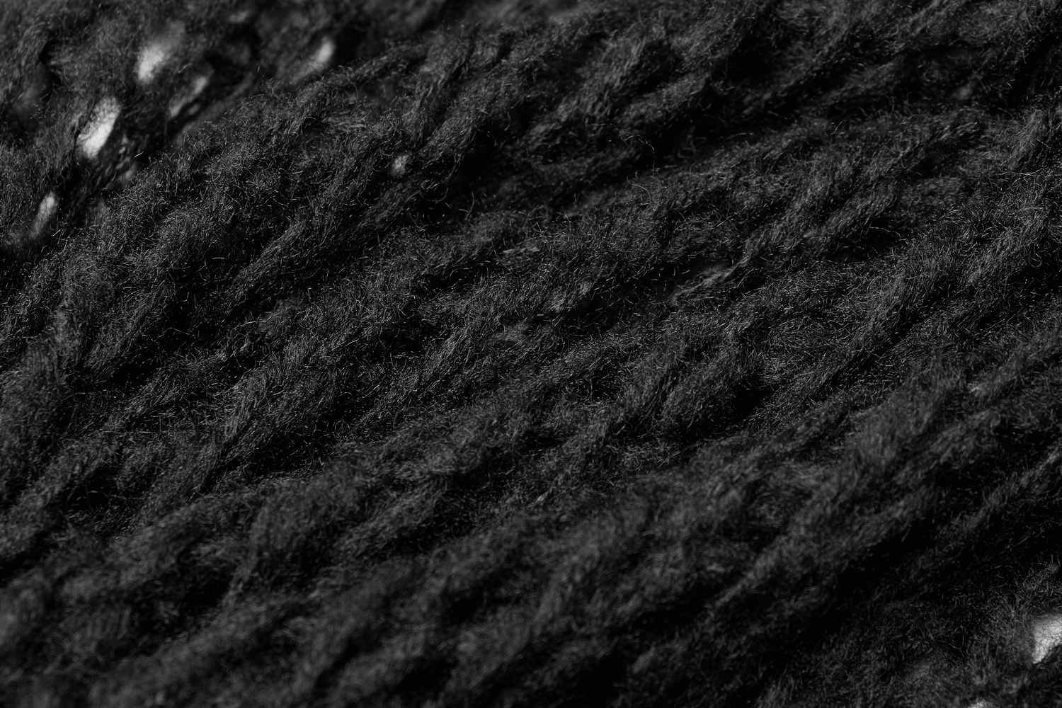 Close-up of textured black knit fabric showcasing intricate design for stylish knitwear.