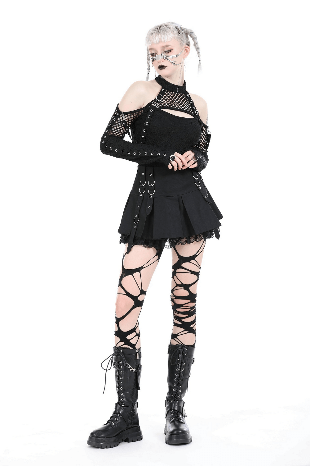 Edgy fashion model in black lace top with cutouts, layered skirt, and lace-up tights, showcasing a daring rockstar vibe.
