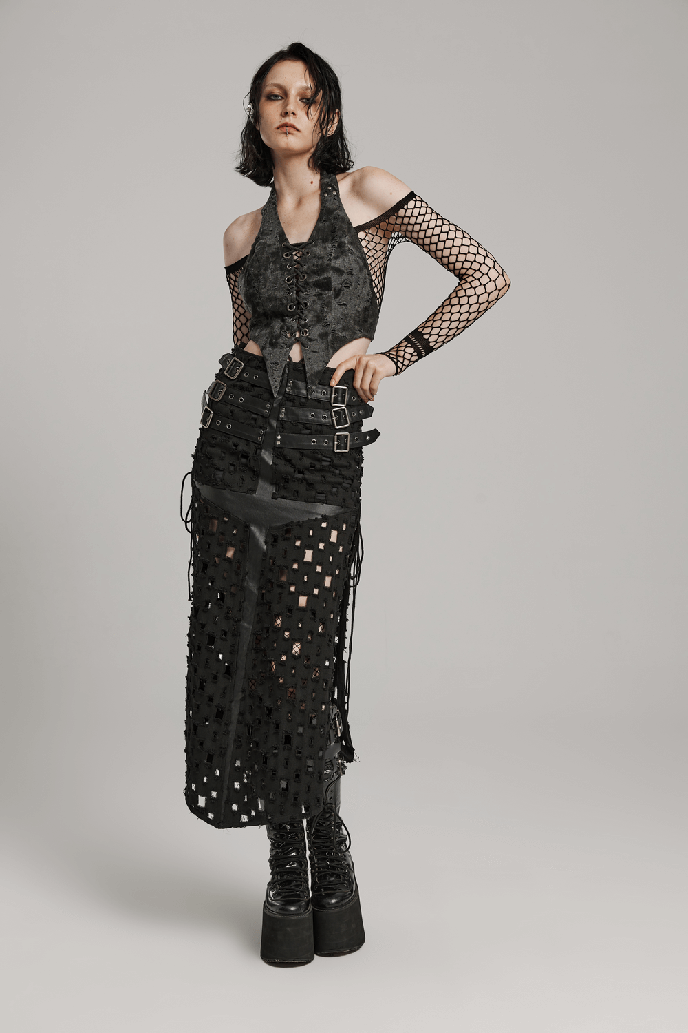 Model in stylish lace-up backless halter crop top with pointed hem and edgy mesh skirt, perfect for a rock-inspired look.