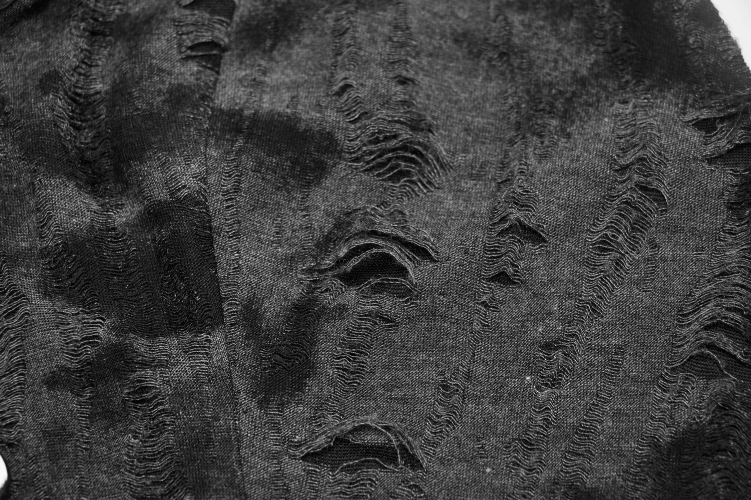 Textured black knit fabric with edgy distressed details and tattered look, perfect for punk rock style.