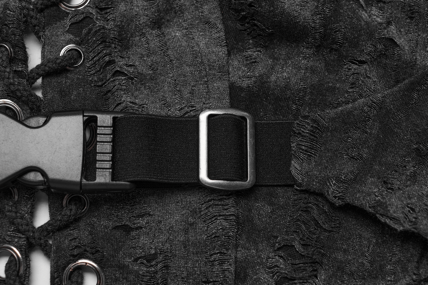 Close-up of edgy black tattered fabric with lace-up detail and adjustable buckle for a stylish backless halter crop top.