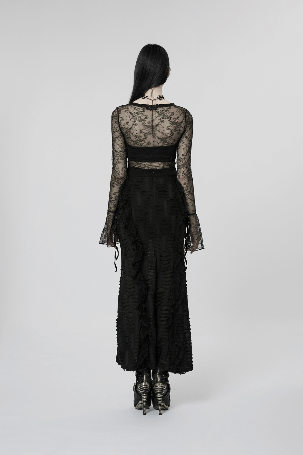 Back view of a stylish gothic layered ruffle skirt with high slit, paired with a lace top and edgy heels.