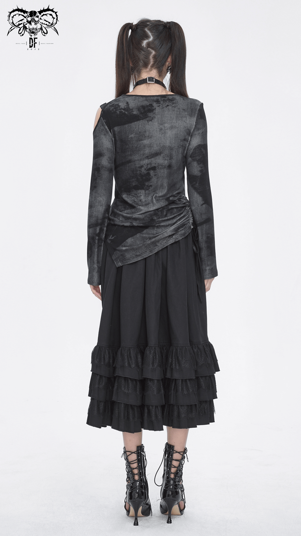 Back view of stylish black punk top with long sleeves and draped detail, paired with a ruffled black skirt and lace-up boots.