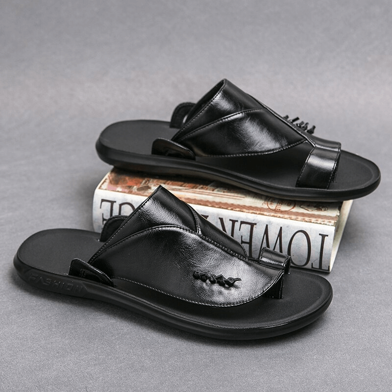 Stylish male PU leather slippers on a stack of books, perfect for casual and luxury looks.
