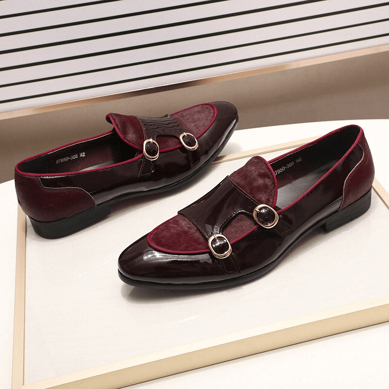 Stylish men's burgundy patent leather loafers with double buckle detail on a display table.