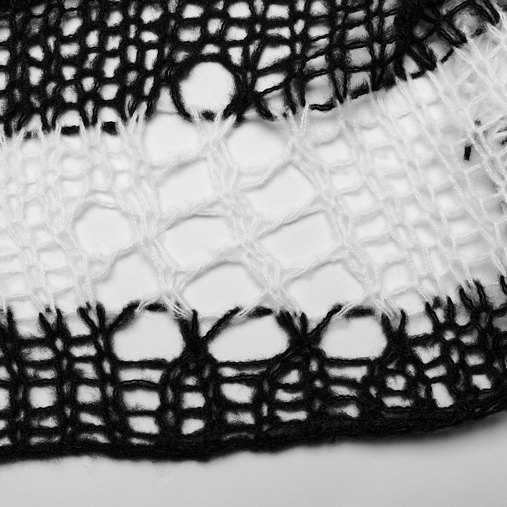 Close-up of mohair knit fabric showcasing striking black and white stripes with edgy irregular holes.