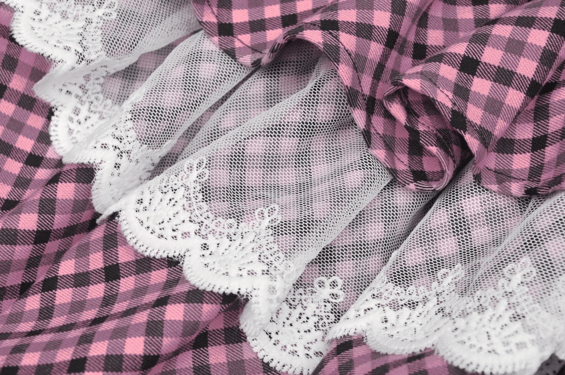 Close-up of a stylish pink plaid skirt with delicate lace trim and ruffled layers, perfect for a trendy outfit.