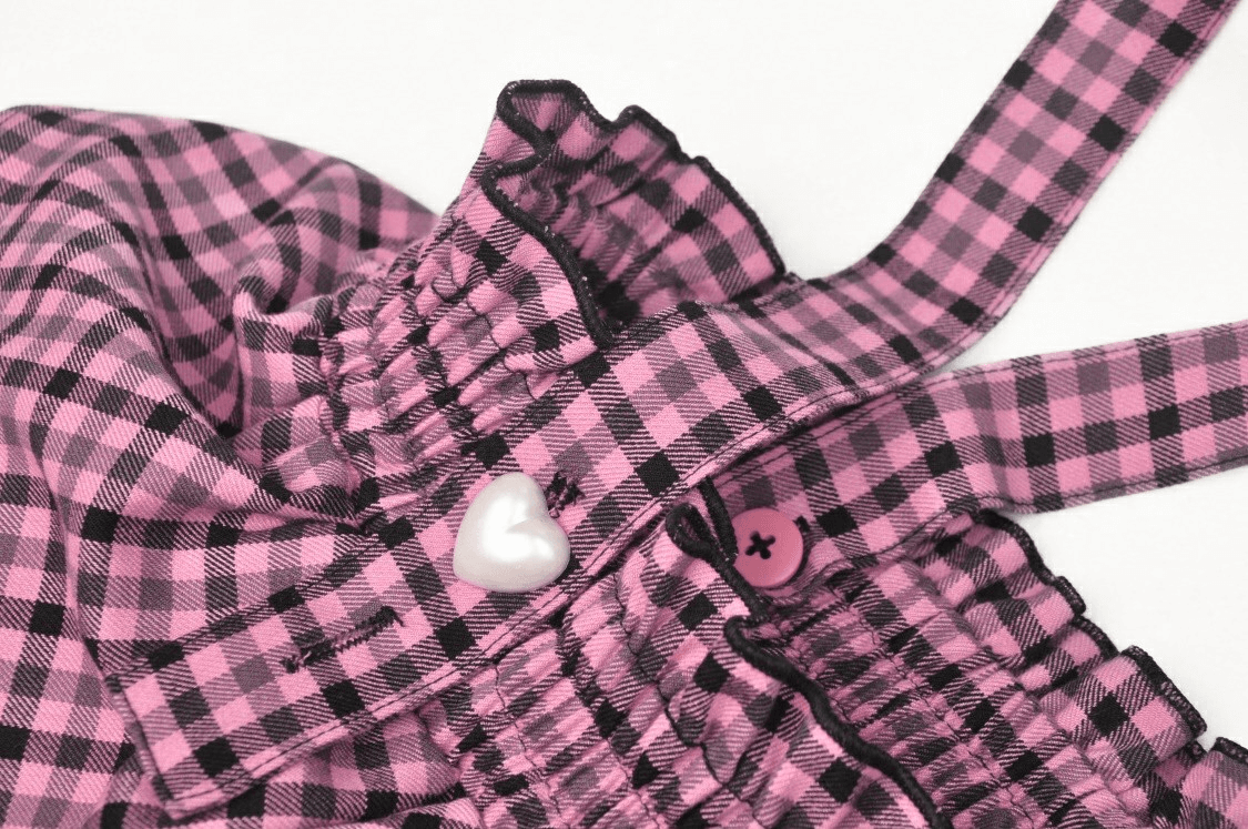 Stylish pink checkered pleated skirt with lace trim and heart button detail.