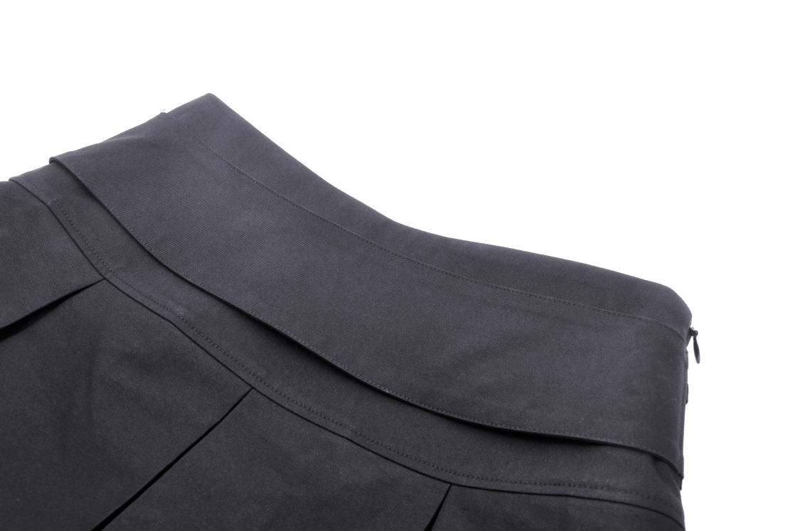 Close-up of stylish black pleated mini skirt showing waistband and pleat details, ideal for a punk rock look.