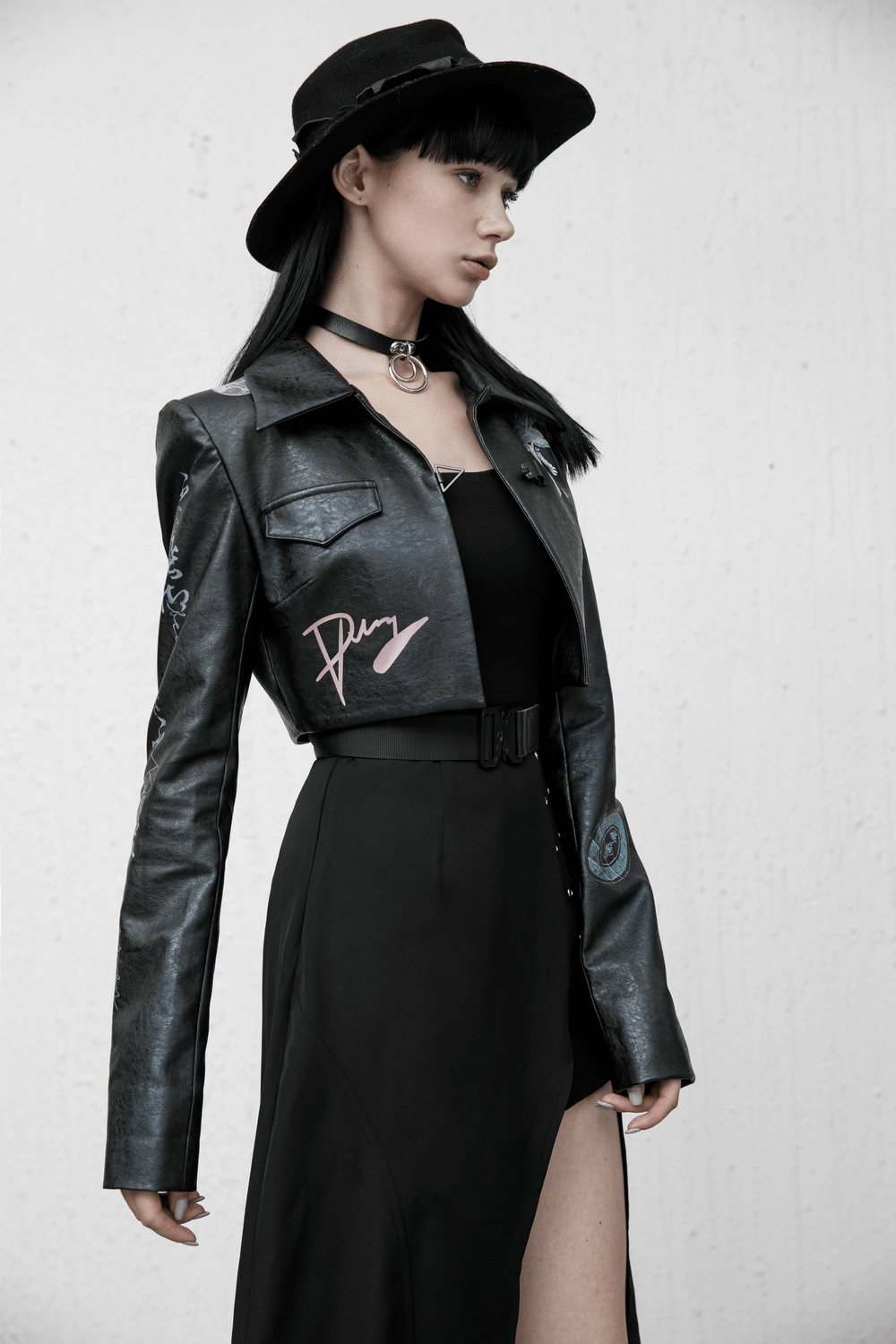 Stylish punk cropped leather jacket with unique prints and front pocket, paired with a chic black outfit.
