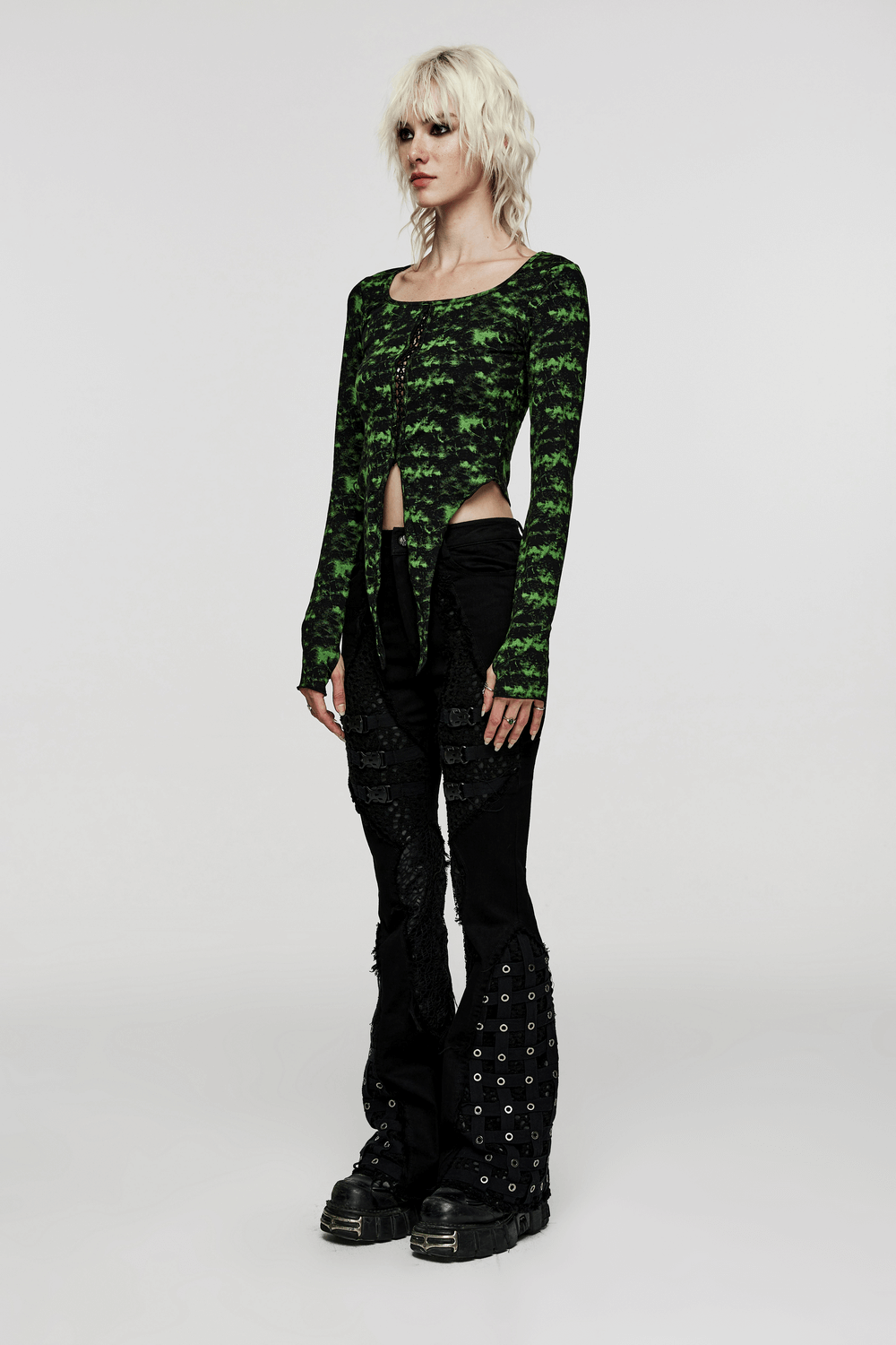 Model in gothic style flared pants with mesh-insert paired with a unique green tie-front top for an edgy look.