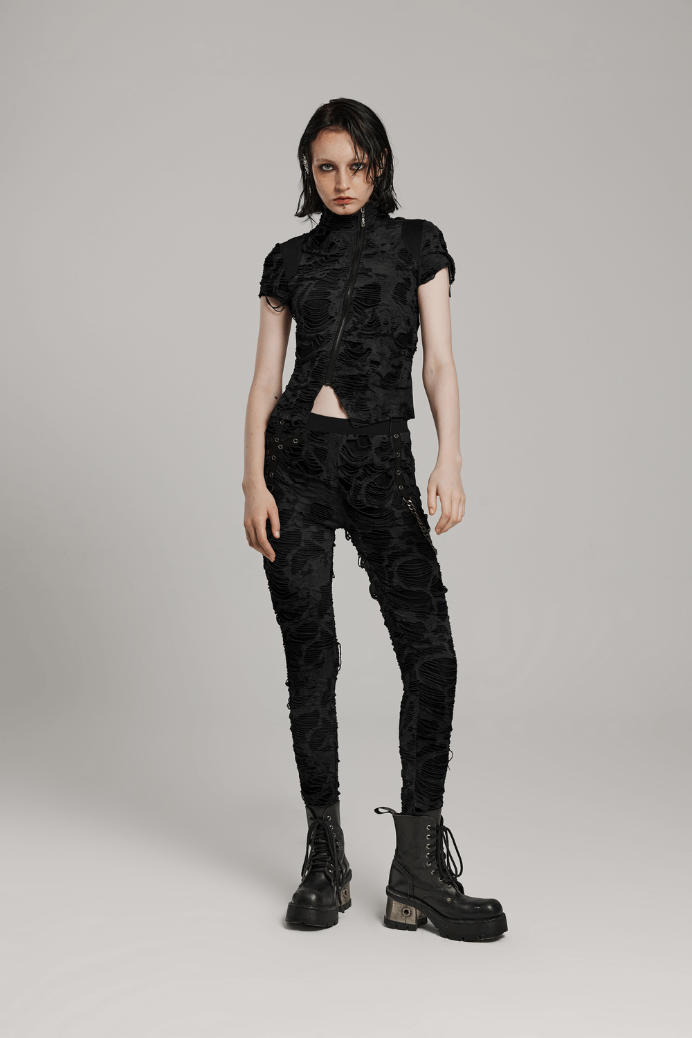 Edgy punk model wearing a black zipped tee and fitted pants, showcasing a rebellious aesthetic with combat boots.