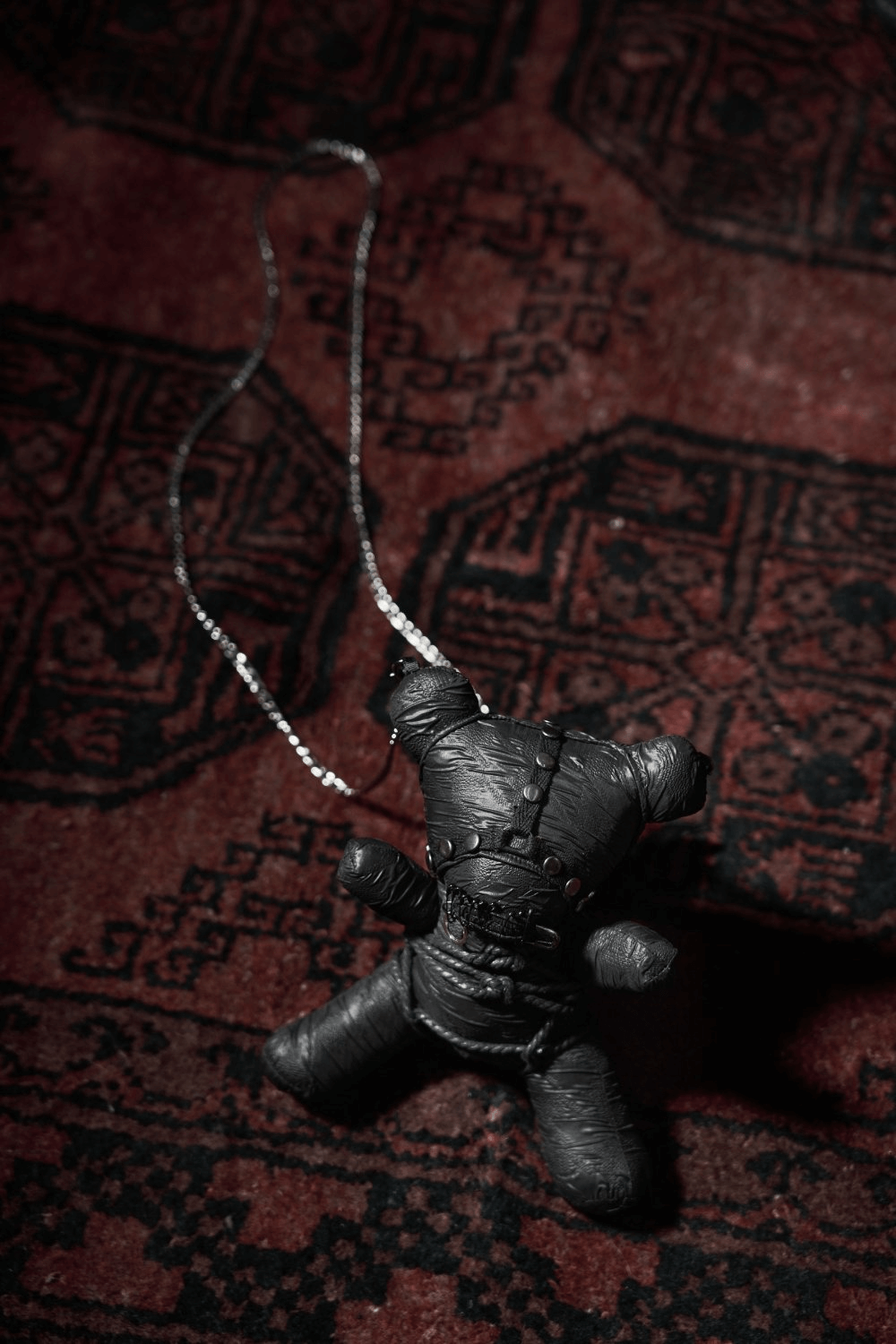 Stylish Gothic Taboo Bear plush with detachable chain on a patterned rug, perfect for dark decor or fashion.