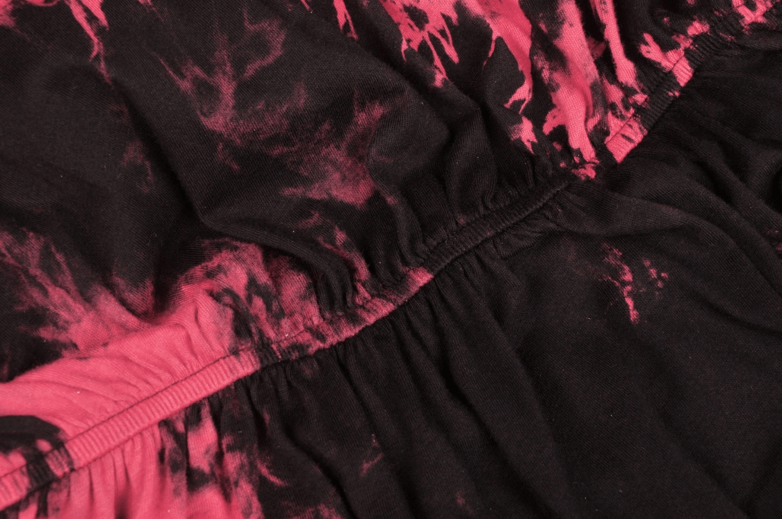 Close-up of dark fabric with vibrant pink splashes, showcasing the edgy design for a punk style dress.