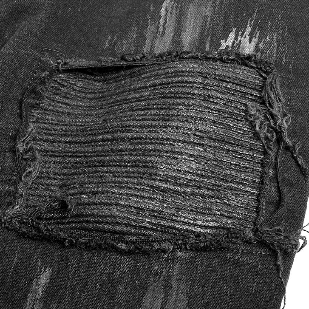 Close-up of distressed black cargo pants showing unique hole-breaking technology and textured fabric details.