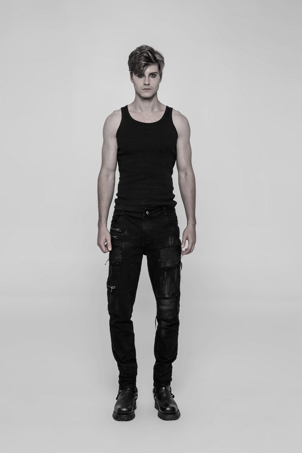 Model wearing stylish ripped black cargo pants with zip details and a black tank top, showcasing a punk aesthetic.