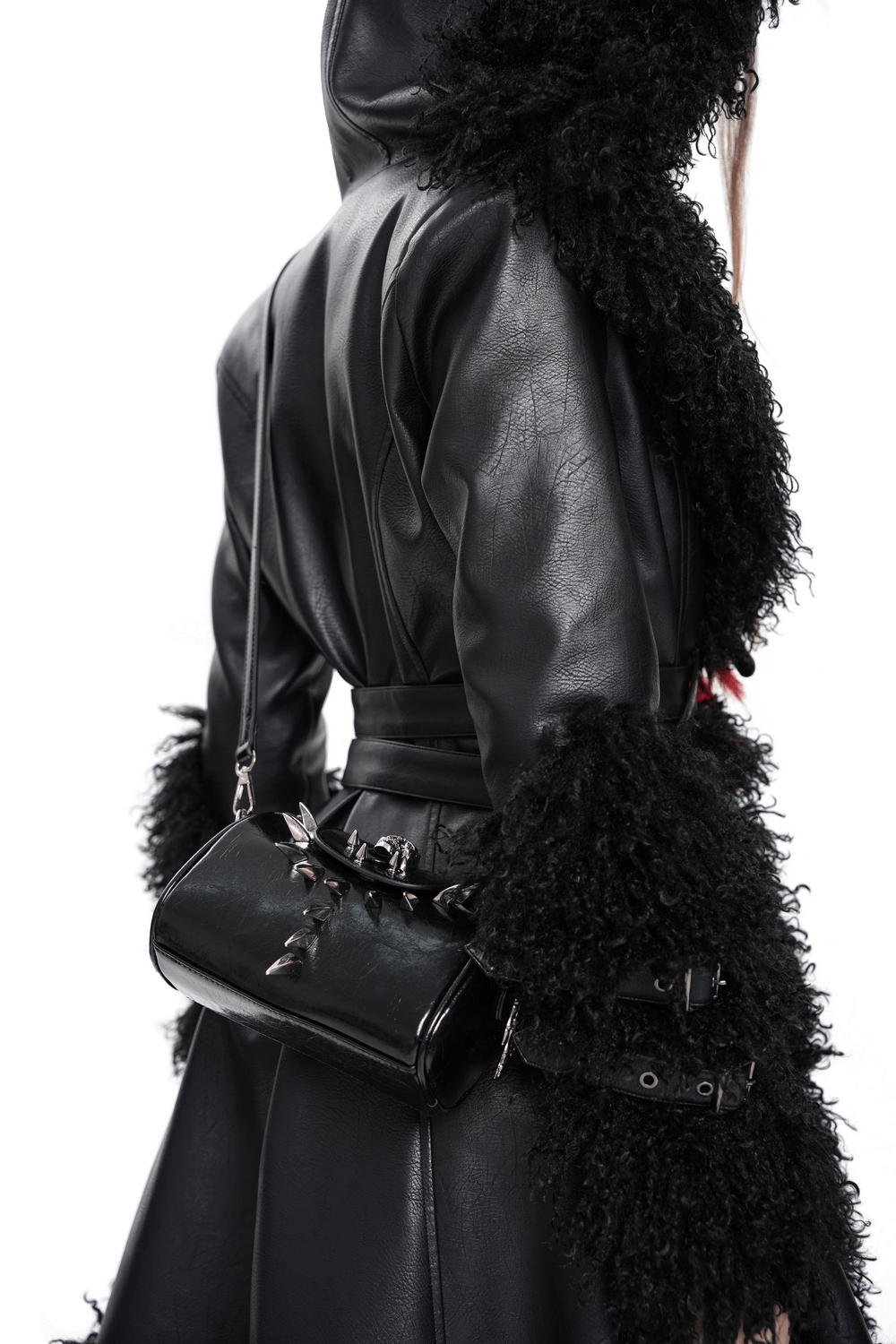 Stylish black leather crossbody bag with bold silver accents worn over a chic textured coat.