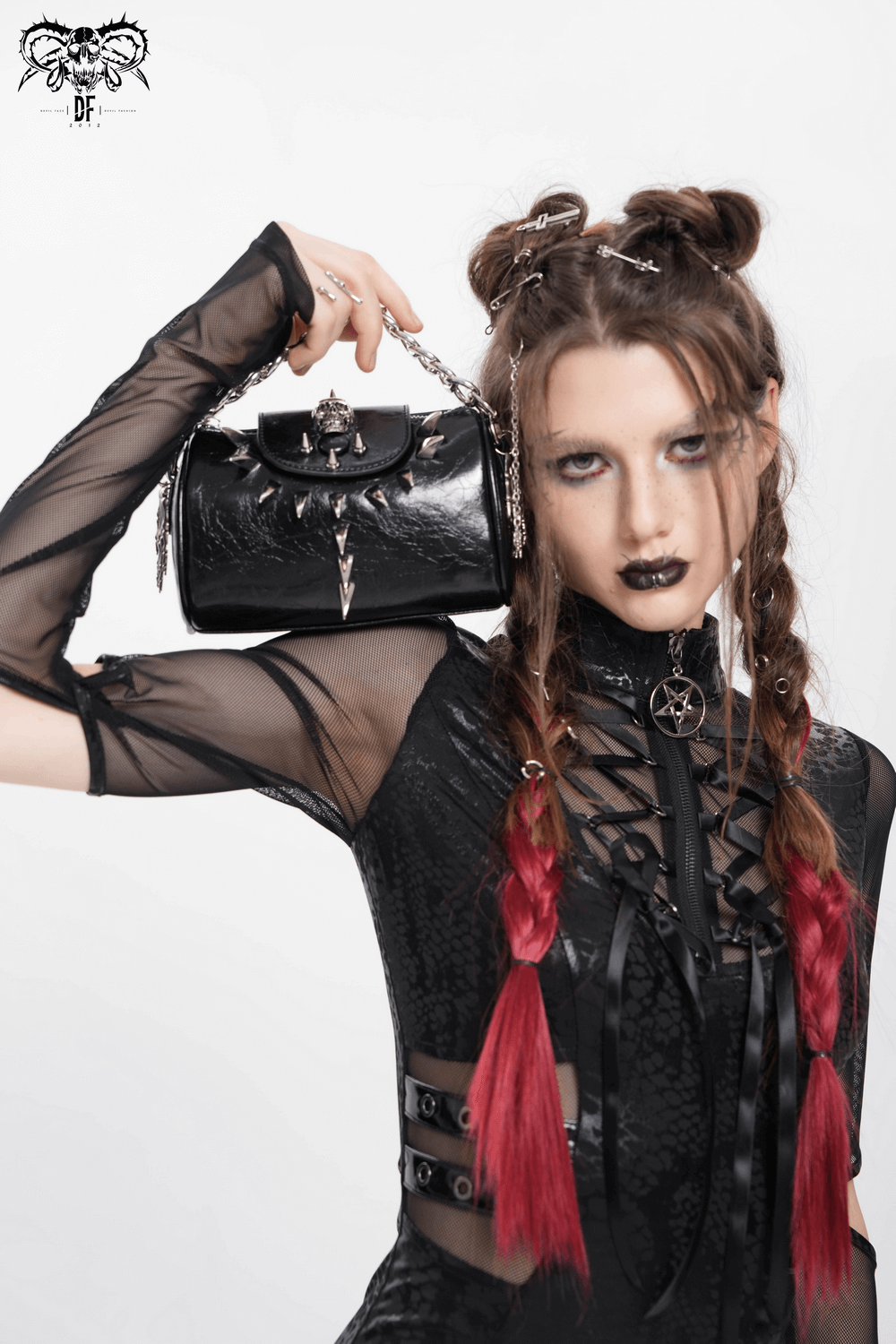 Gothic model showcasing a stylish black leather bag with silver hardware, wearing edgy attire and dramatic makeup.