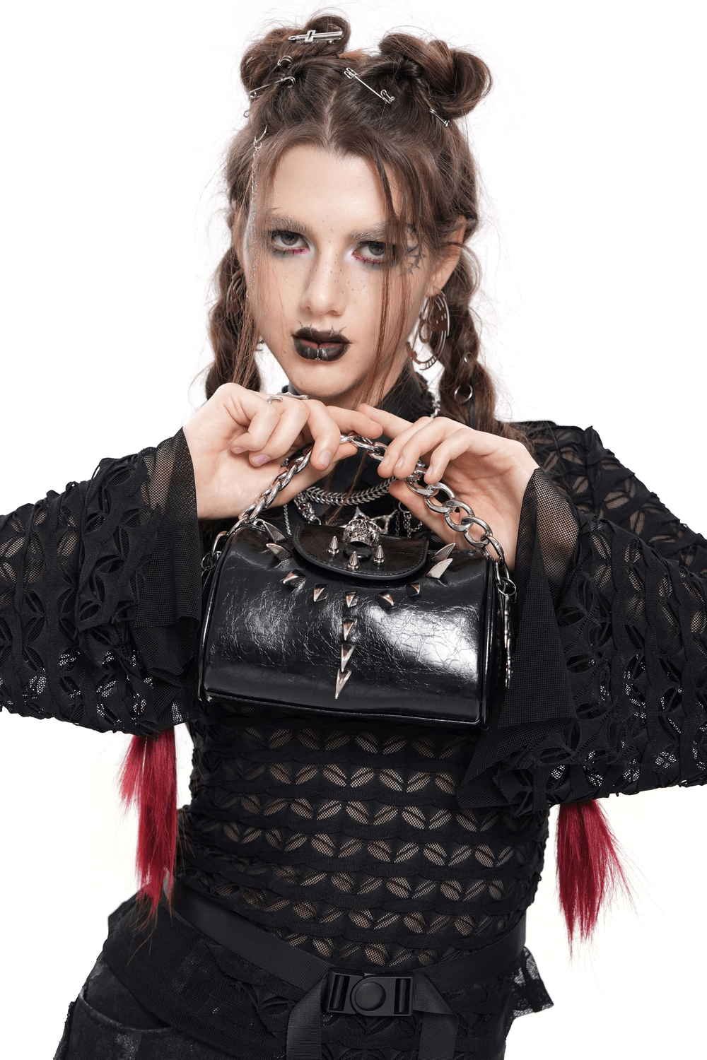 Trendy black leather shoulder bag with bold silver chain and edgy details, styled by a model in a chic outfit.
