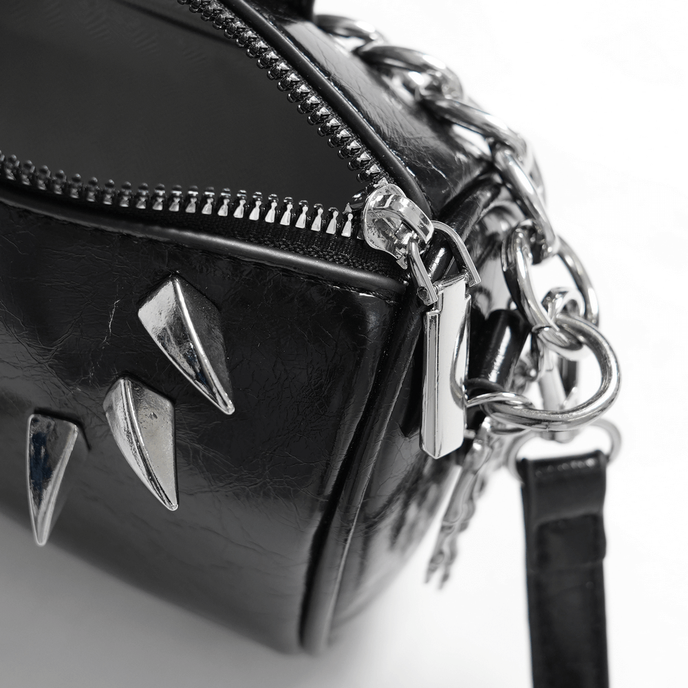 Close-up of stylish black leather shoulder bag with bold silver hardware and zipper.