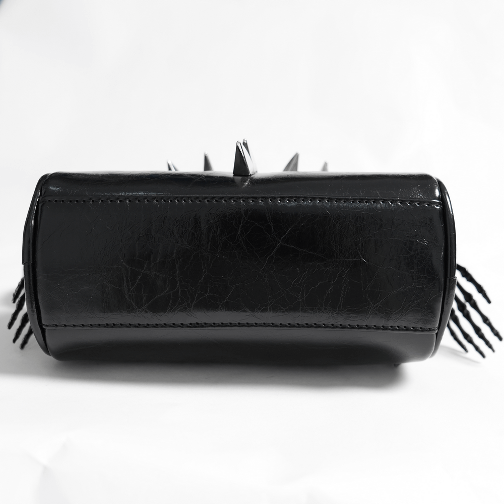 Bottom view of a stylish black leather shoulder bag with spiked accents and sleek design.