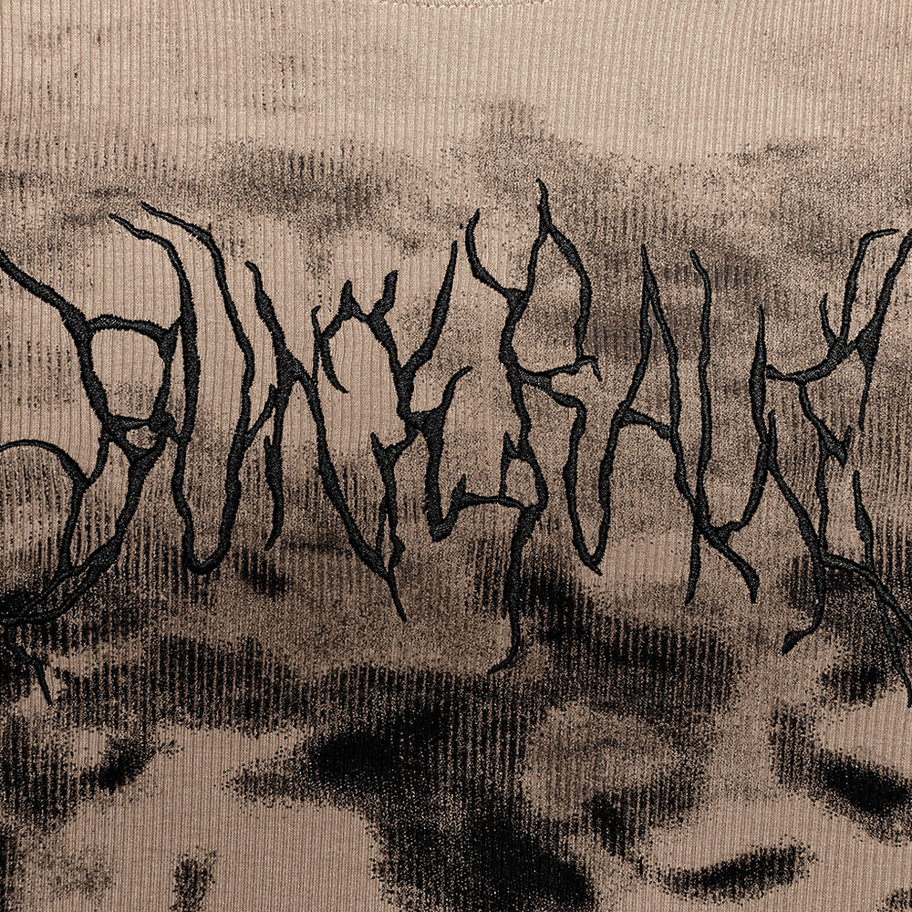 Close-up of embroidered 'Punk Rave' lettering on stylish tie-dye turtleneck sweater with a textured background.
