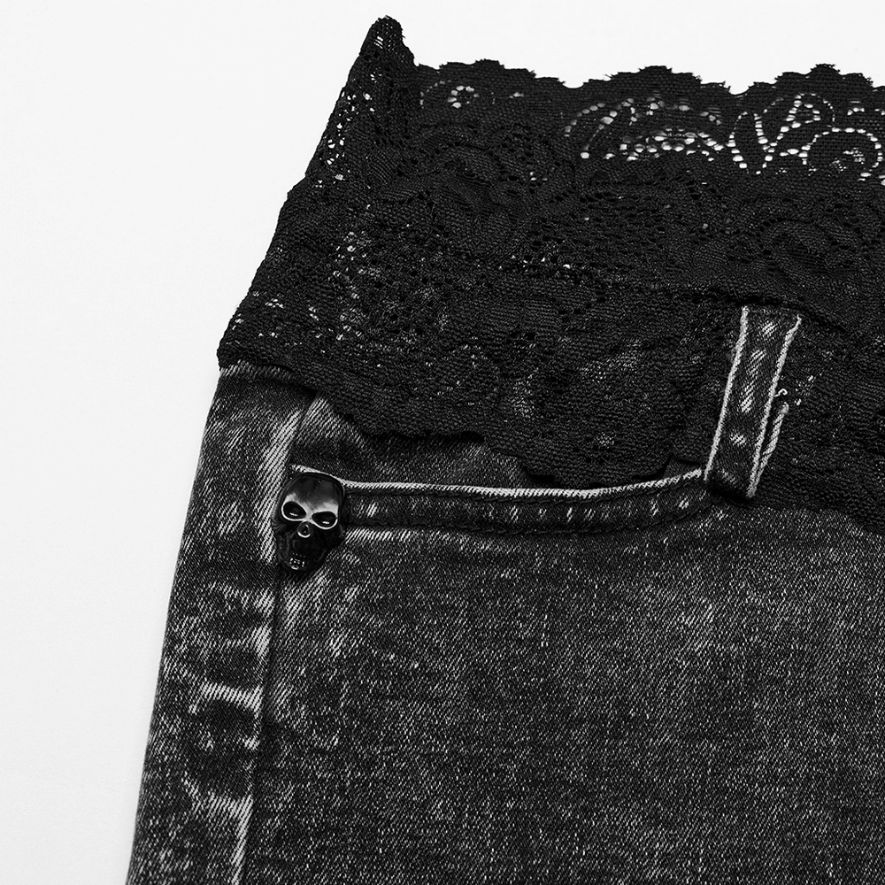 Close-up of stylish high-waisted denim shorts featuring elegant black lace trim and unique skull button detail.