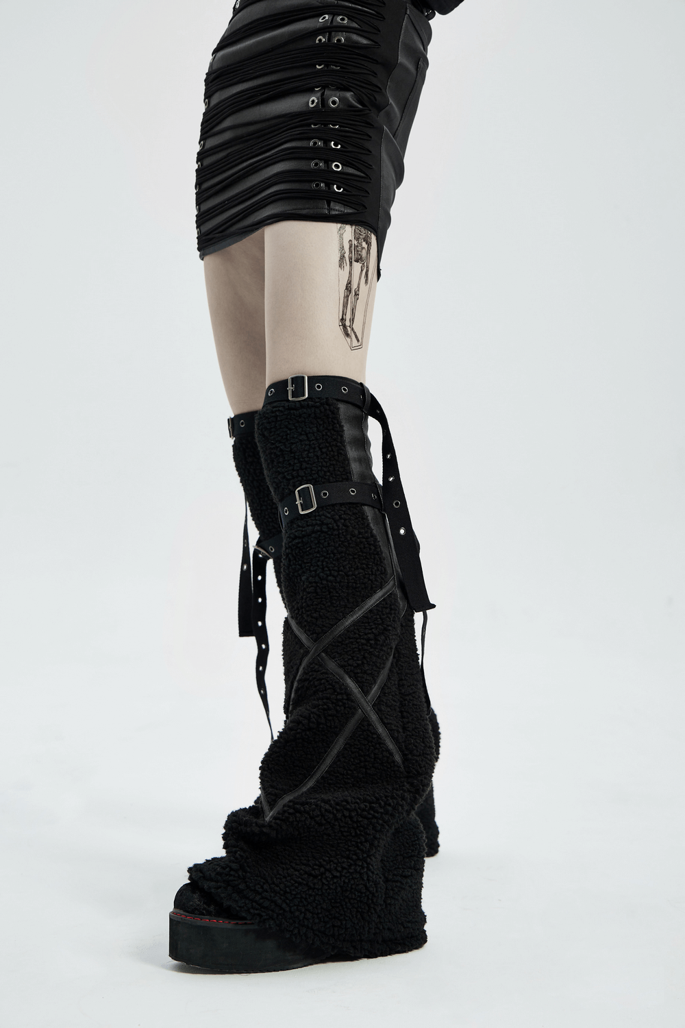 Stylish punk-inspired black leg warmers paired with a chic mini skirt, featuring edgy straps and a trendy tattoo.
