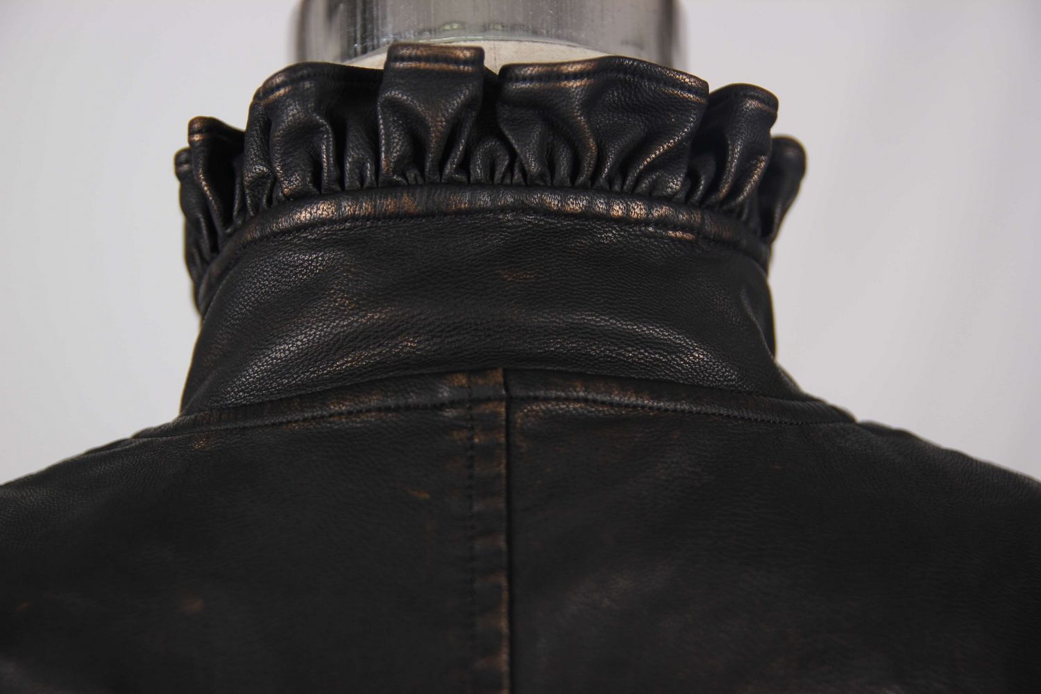 Close-up of the stylish ruffled collar of a women's black PU leather steampunk vest.