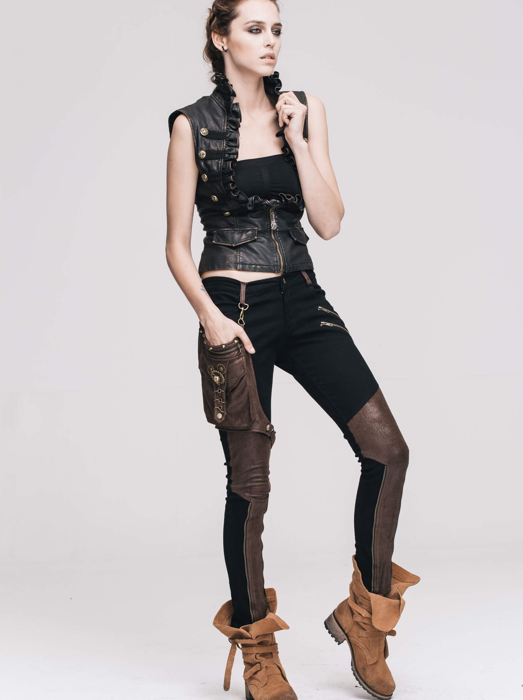 Stylish woman in a black steampunk PU leather waistcoat and chic black pants with brown accents.