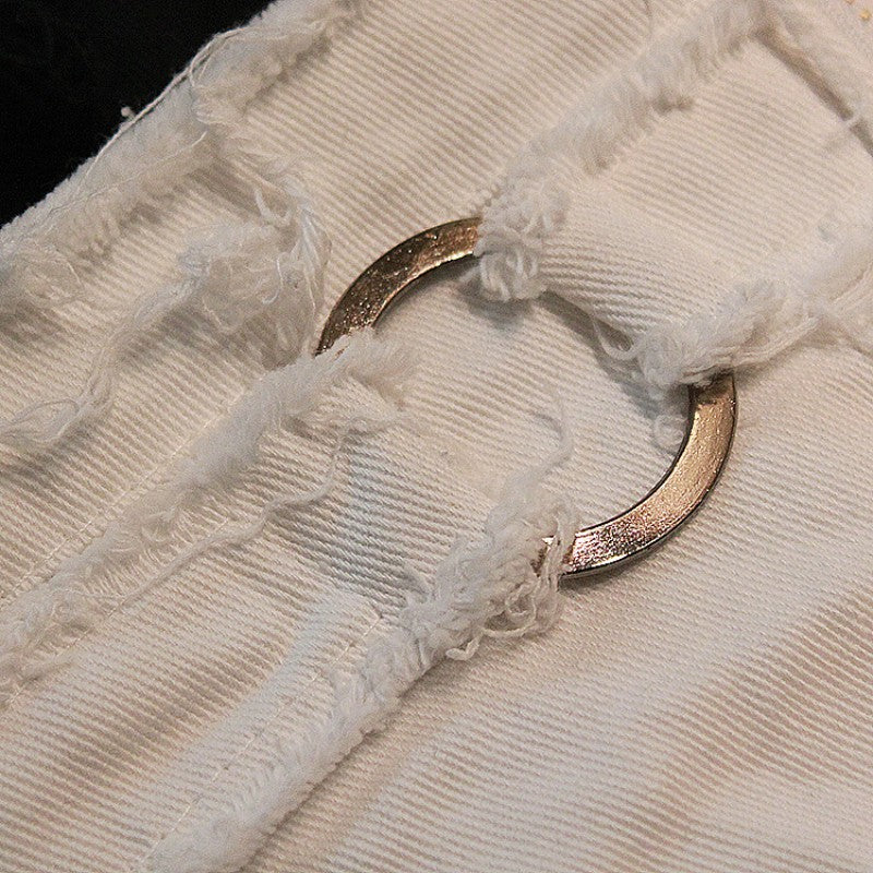 Close-up of white denim shorts with lacing detail and metal ring for a stylish grunge look. Perfect for summer fashion.