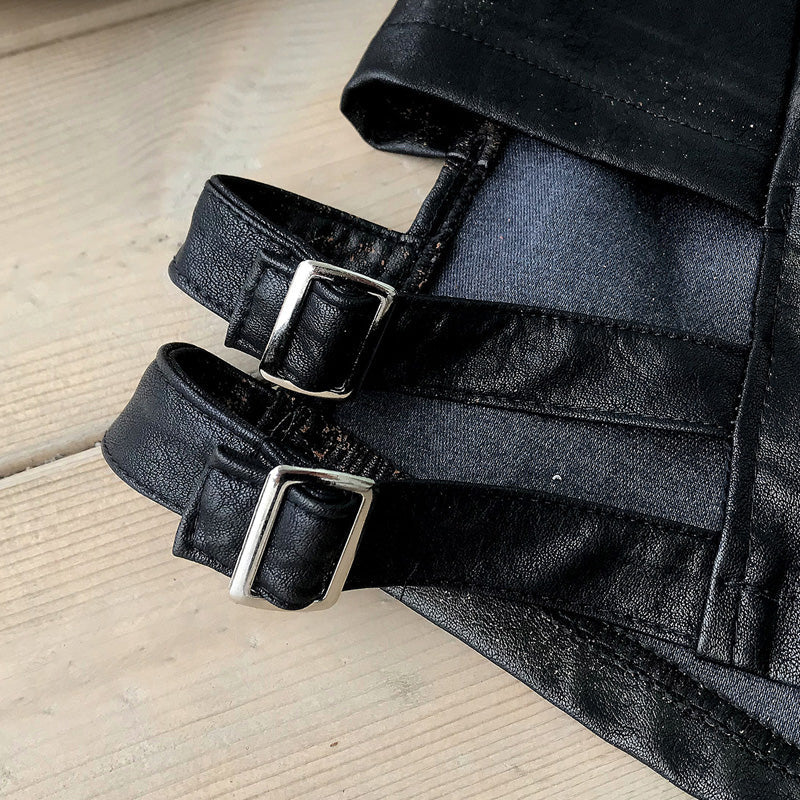 Close-up of black imitation leather straps on women's high waist shorts, showcasing adjustable buckles.