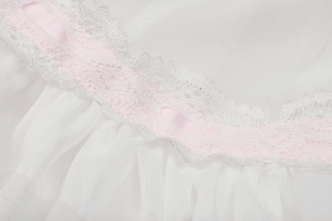 Close-up of the delicate lace and pink ribbon trim on a sweet white pleated mini skirt.