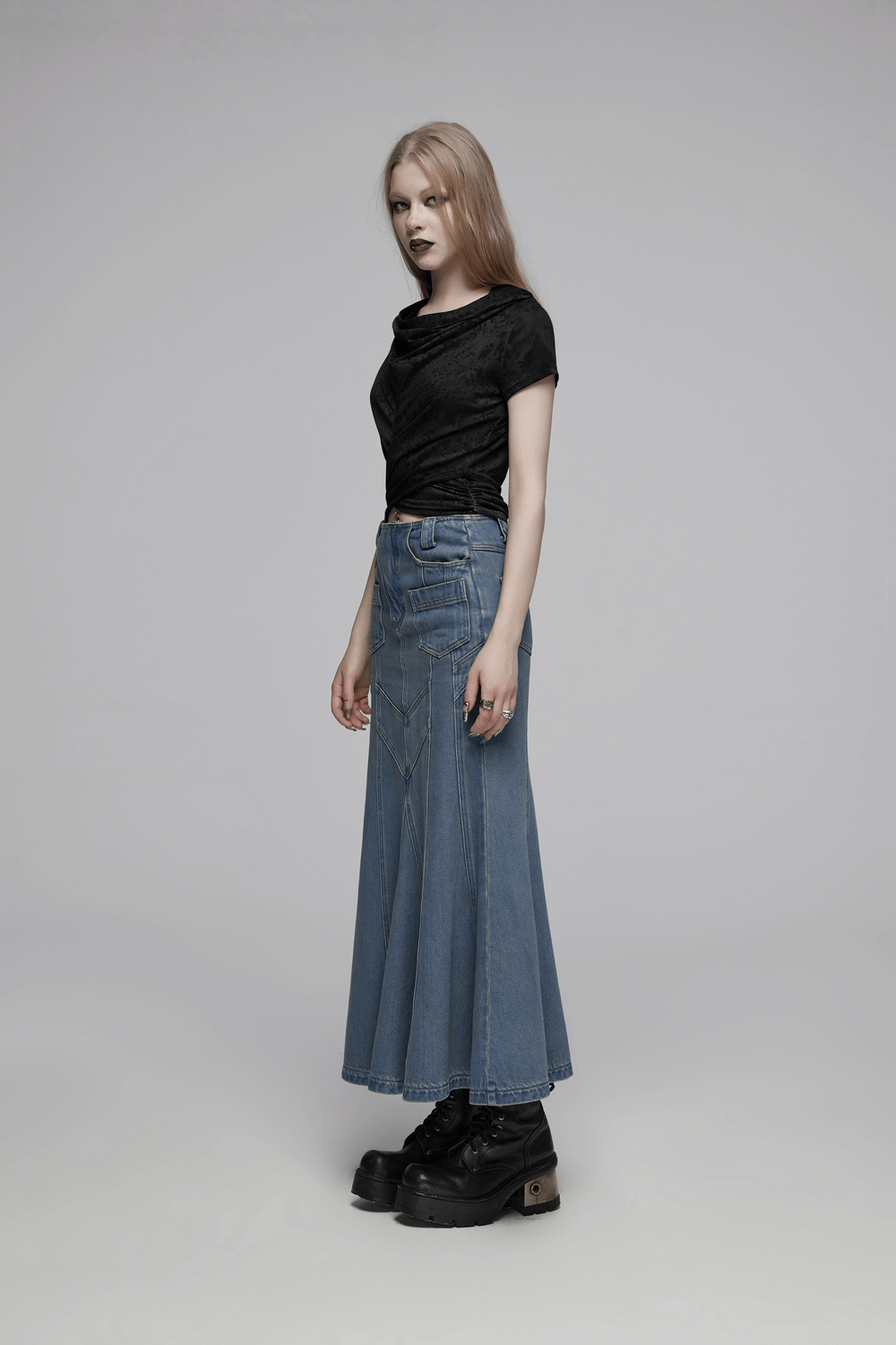 Model wearing a black swing collar hooded cropped top with criss-cross hem paired with a long denim skirt and platform shoes.