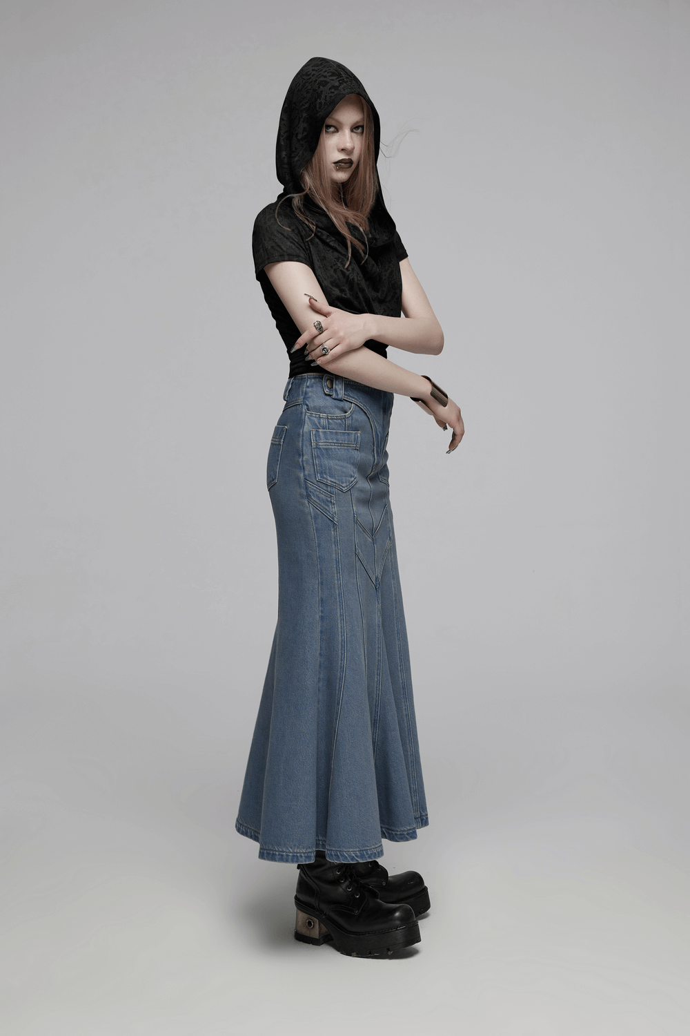 Model wearing a punk-style black hooded crop top with a long denim skirt, showcasing a trendy outfit ideal for modern fashion.