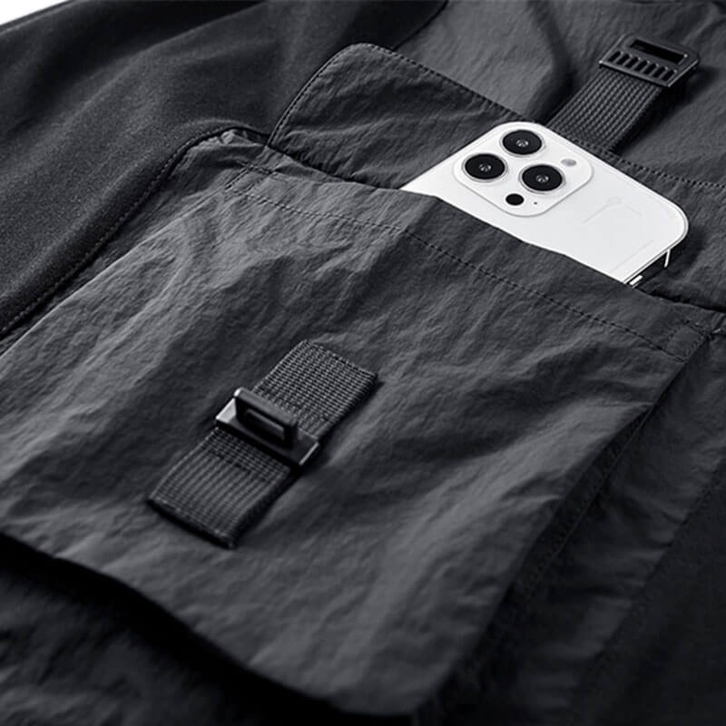 Close-up of a black tactical t-shirt pocket holding a smartphone, showcasing multi-pocket functionality.