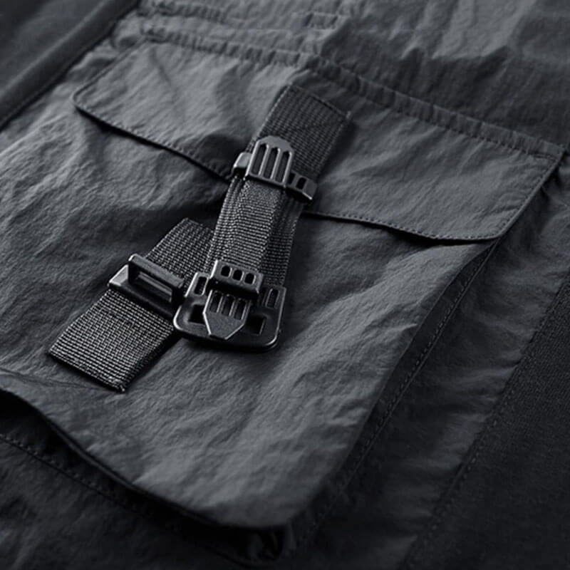 Close-up of tactical black shirt pocket with adjustable strap, showcasing practical style and functionality.
