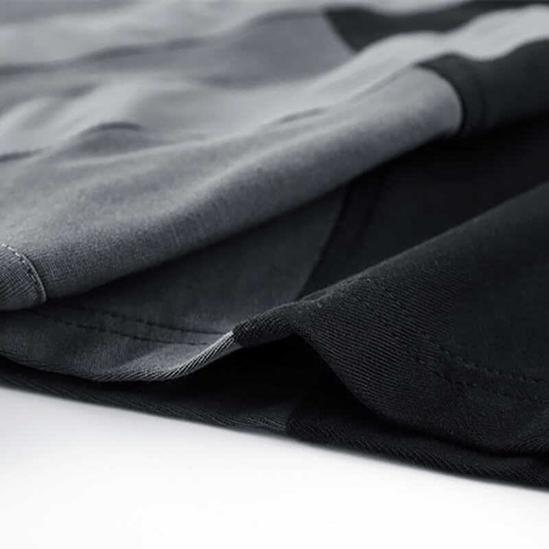 Close-up of men's tactical patchwork t-shirt showcasing stylish gray and black fabric layers and stitching.