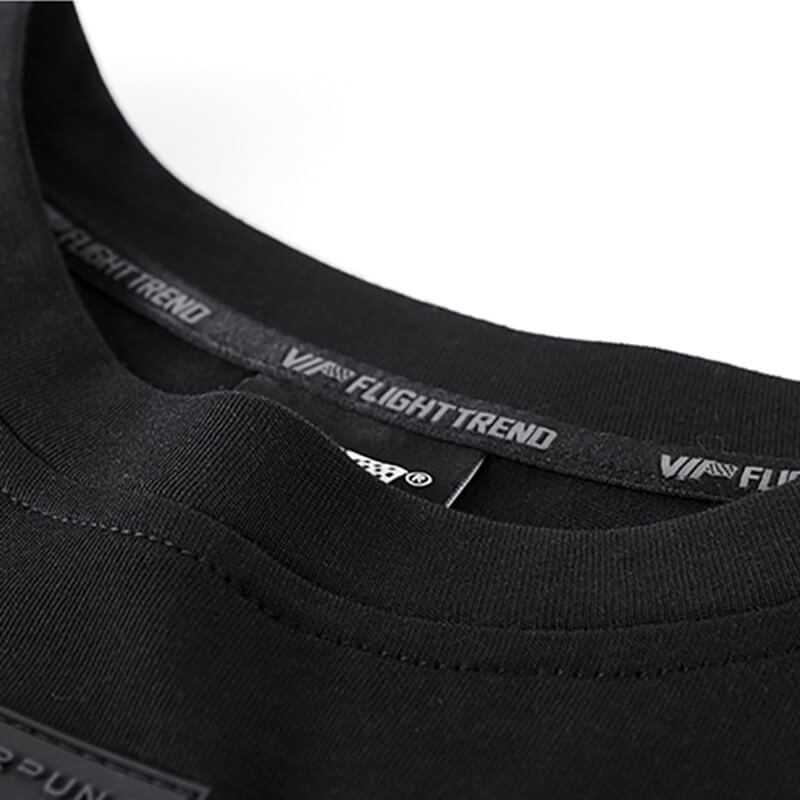 Close-up of the neckline of a men's tactical patchwork t-shirt showing stylish black fabric and label details.