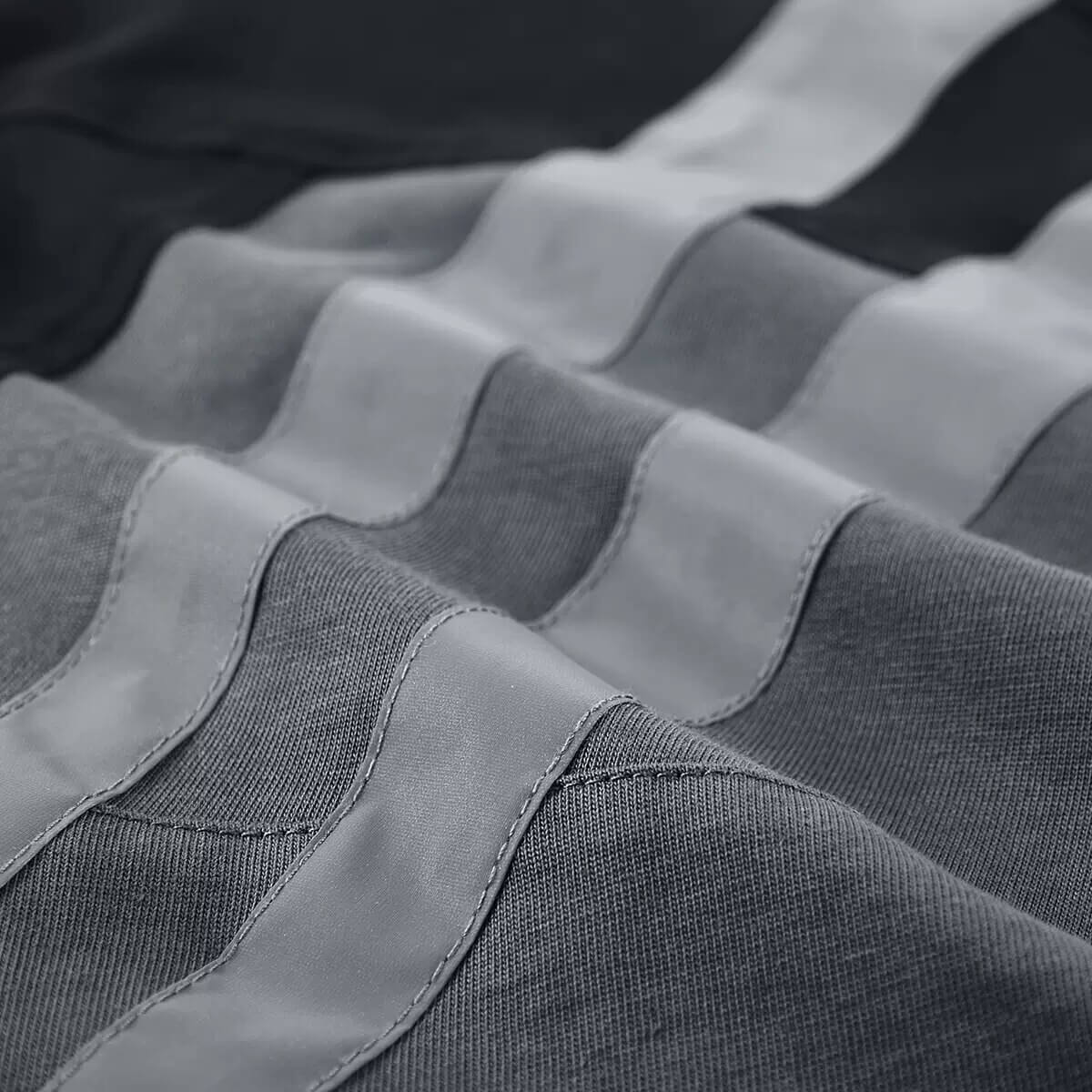 Close-up of the reflective striped splicing on a tactical patchwork T-shirt for men.