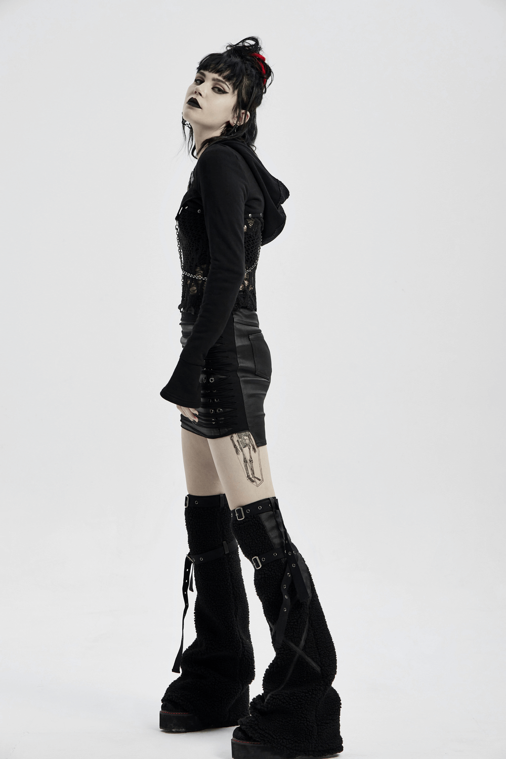 Model showcasing a steampunk-inspired outfit with a skeletal glove, black clothing, and platform boots.