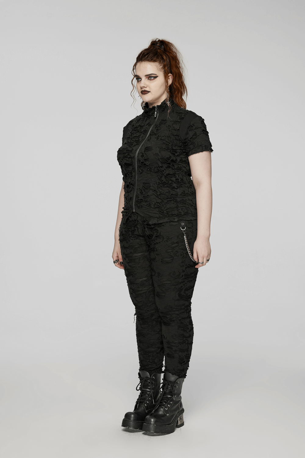 Black tattered punk top with front zipper and slim fit, worn with matching pants and chunky boots for an edgy look.