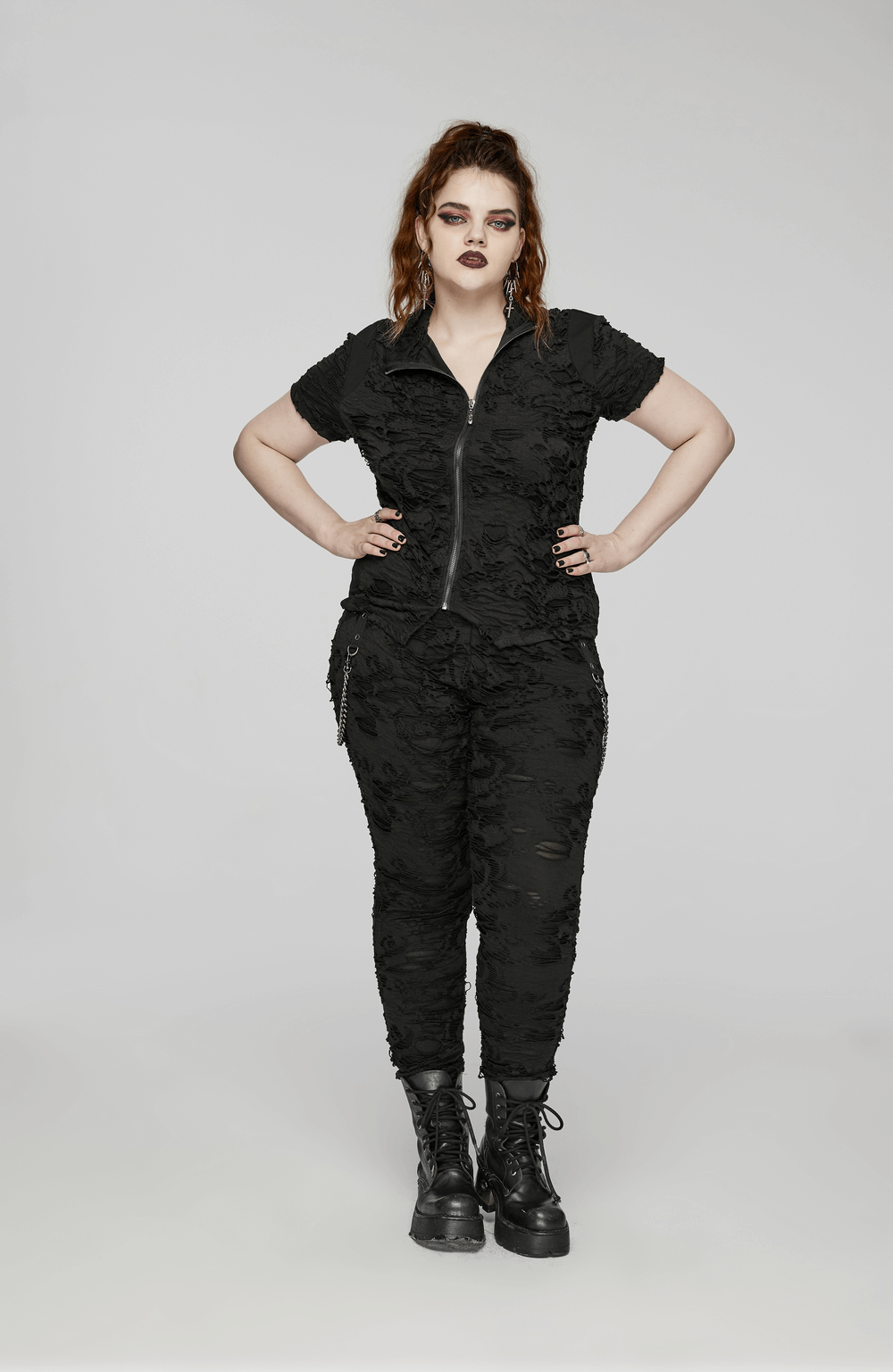 Edgy black tattered punk top with front zipper and slim fit, styled with matching pants and combat boots.